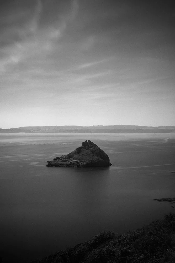 Black and white image of an island with land
          in the foreground