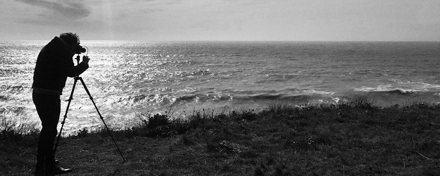 Black and white image of a photographer taking a landscape image